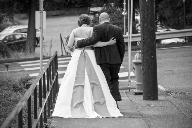 Bride and Groom seen from behind walking arm in arm down street